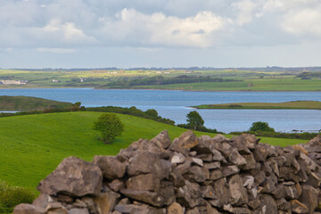 Irish landscape, green meadow, river Moy in the background, stone wall in the foreground
