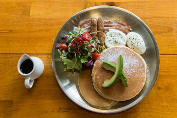 breakfast with pancakes, sausages and vegetables on the table