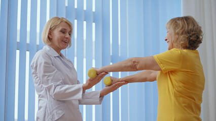 A patient smiles while doing exercises under a doctor's supervision in a clinic