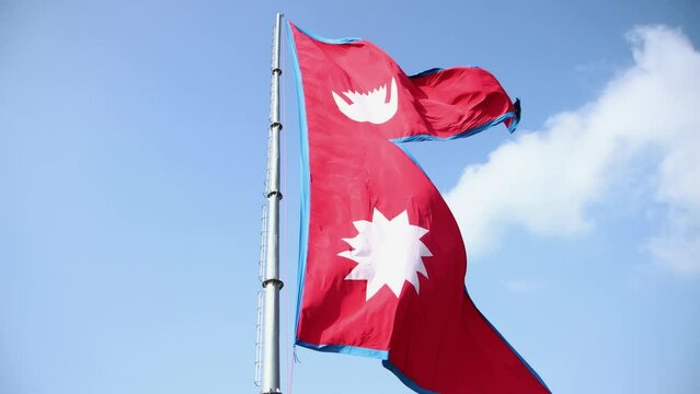 Nepal national flag. Nepal flag waving in the blue sky. Nepal Flag Flying High With Pride.