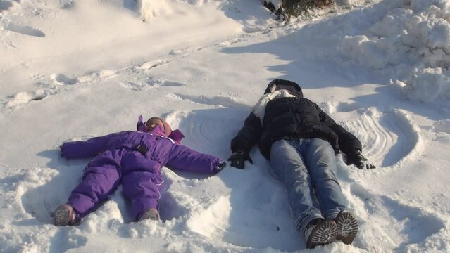 Mother and Child Making Angels in Snow, Family Playing in Snow