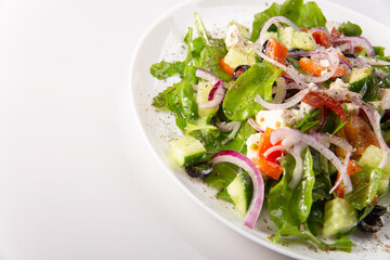 Traditional greek salad with fresh ingredients, feta cheese, olives, red tomatoes, cucumbers and greens