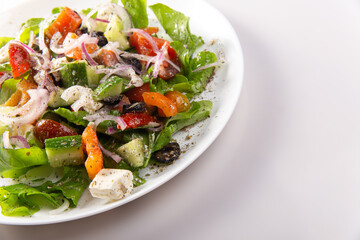Traditional greek salad with fresh ingredients, feta cheese, olives, red tomatoes, cucumbers and greens
