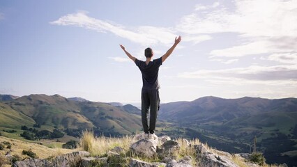 Man raising his hands on the rock on the peak of the mountain