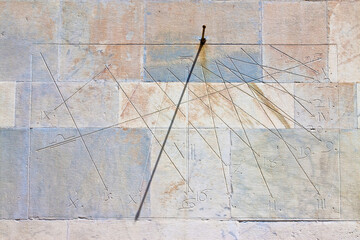 Ancient sundial on a stone wall with shadow marking the hours