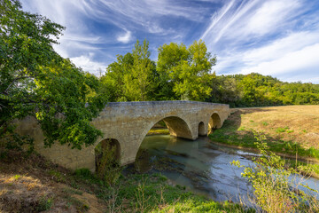 Fototapeta na wymiar Romanesque bridge of Artigue and river Osse near Larressingle on route to Santiago de Compostela, UNESCO World Heritage Site, departement Gers, France