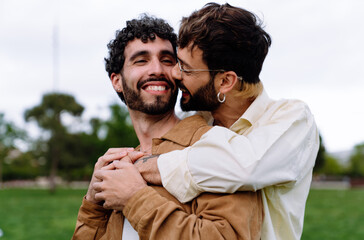 Happy gay couple embracing in back hug while in park