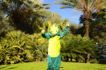 Masquerade, Halloween, Purim. Child in fancy dress dinosaur pajamas. A boy in the park enjoys the...