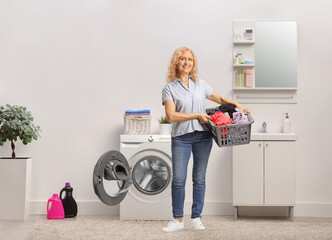 Mature woman holding a laundry basket with clothes in a bathroom