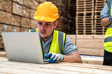 Wood worker man utilizes with laptop on job site, combining technology and expertise in wood...