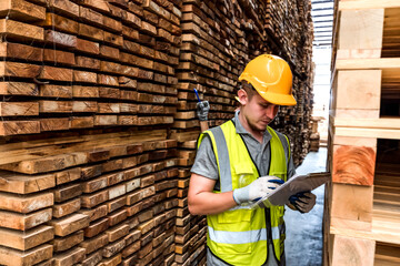 Wood worker manager checking lists on clipboard working in distribution wood factory