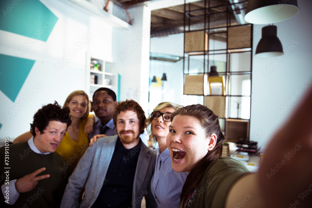 Wall mural young people taking a group selfie in modern office