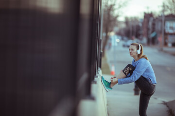 Happy runner tying her sneakers before a morning jog on a city street