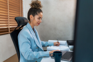 A curly-haired professional young woman, diligently working in a sleek modern office environment, expertly navigating her desktop computer, seamlessly integrating technology and productivity.