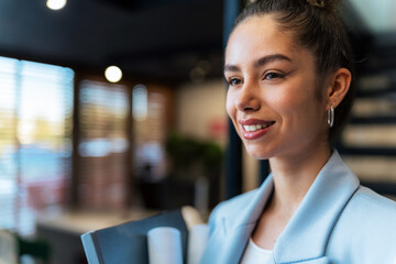 Successful businesswoman, she leaves her modern glass office, descending the staircase with important documents in hand.