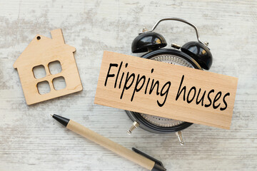 Flipping Houses text on a wooden block. a table clock