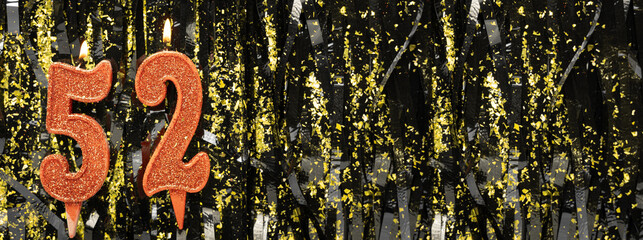 Burning red birthday candles on glitter tinsel background, number 52. Banner.