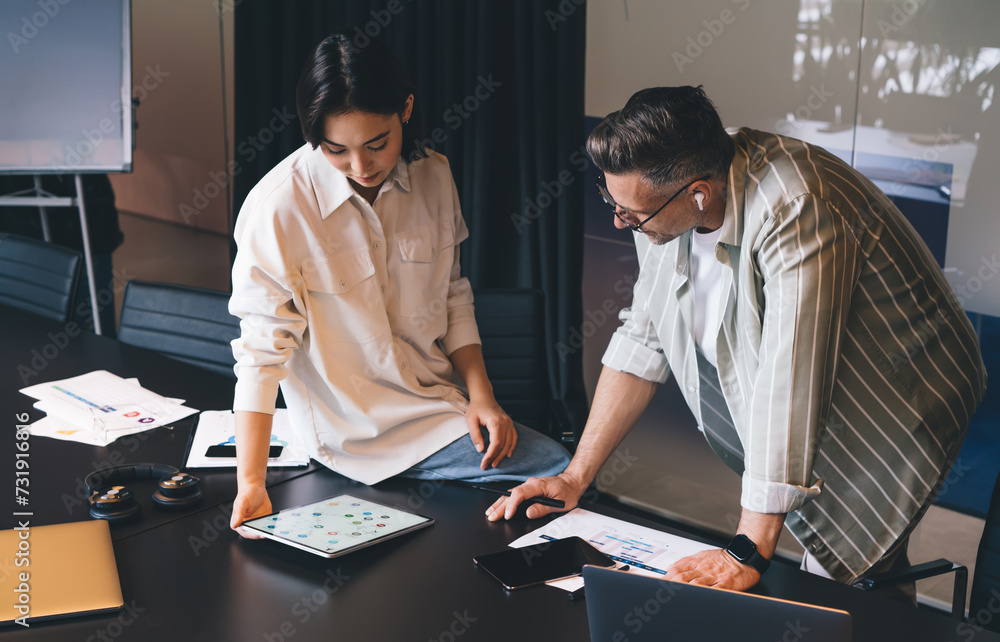 Poster male and female colleagues creating product design during brainstorming at table desktop, profession