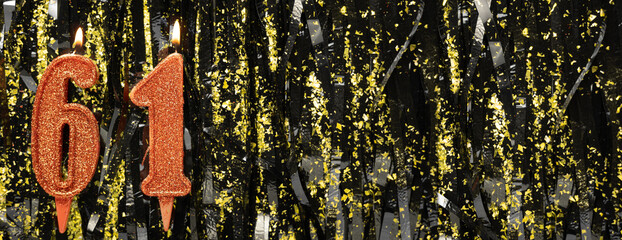 Burning red birthday candles on glitter tinsel background, number 61. Banner.