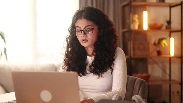 Tired young curly woman feels satisfied with distance remote work well done at home Calm self employee female relax after hard working day finished project on laptop computer indoors