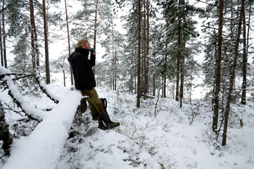 Man resting during hike in winter forest