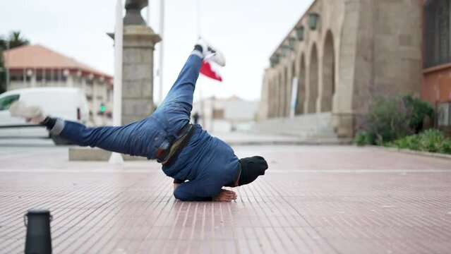 latin American breakdancer guy performing downrock or floor based footwork on the street