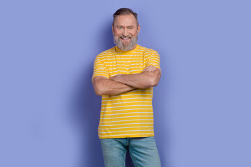 Photo of cool handsome retired man with gray white beard dressed striped t-shirt standing arms crossed isolated on purple color background