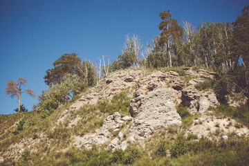Fototapeta na wymiar Scenic View of Rocky Hill with Sparse Trees and Clear Blue Sky in the Background
