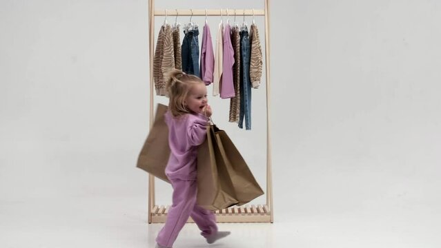 Wooden clothes hanger with children's wardrobe. The little girl chooses clothes. Concept of advertising children's things and shopping