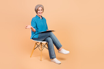 Full length photo of friendly person on chair hold checklist look empty space invite for consultation isolated on beige color background