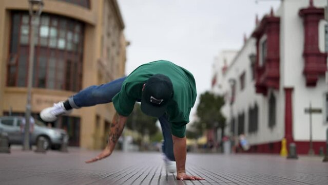 latin American breakdancer guy performing downrock or floor based footwork on the street