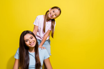 Photo of pretty sweet little sisters wear t-shirts having fun empty space isolated yellow color...