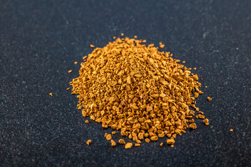 A close up view of dried coffee granules in a pile on a dark marble platter