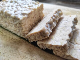 Sliced ​​raw soybean tempeh, a typical Indonesian food on a cutting board.