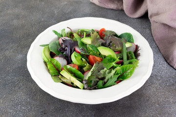 Fresh mix salad with avocado, tomato and radish on a white background. Avocado salad. 