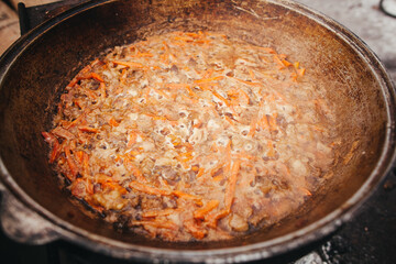 Large old cauldron with handles full of delicious food cooking on an open fire outdoors