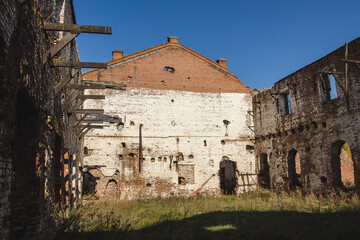 Ruins of an old industrial building with large empty rooms and brick walls.