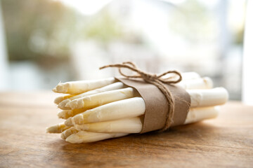 Bunch of fresh white asparagus. Seasonal spring vegetables on a wooden table. Kitchen scene for the seasonal gastronomy. Close-up with short depth of field.