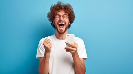 A young man celebrating a victory or a lottery win with a phone in his hand shouting with joy