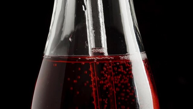 Close-up of red soda being consumed through a transparent straw, and it rises along the straw.