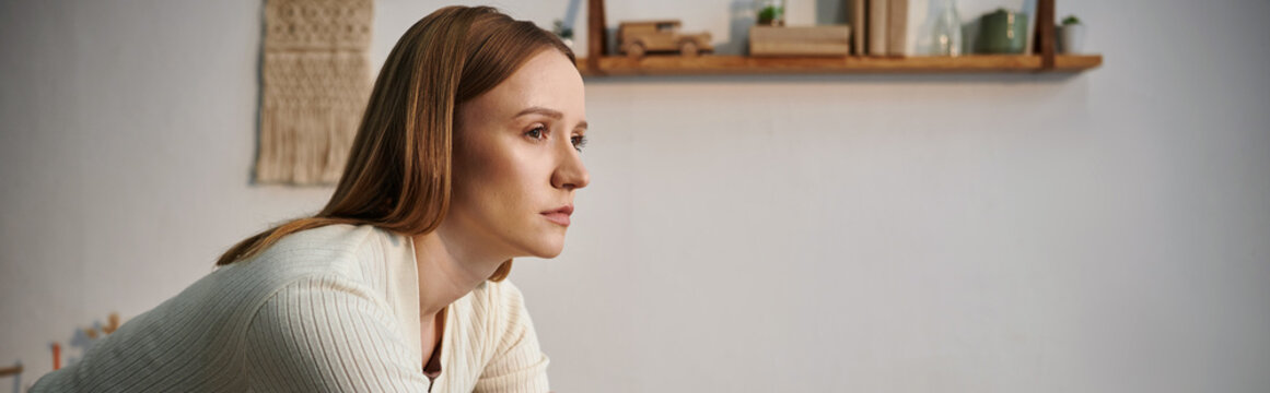 young depressed grieving woman looking away in dark nursery room at home, horizontal banner