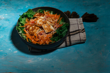 green salad with carrot and pan fried  halloumi cheese, kitchen textile napkin, served on blue textured background