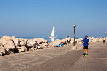 An elderly man is jogging along the seaside in the morning day, Piran - 731973071