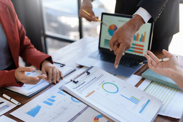 A group of business professionals engaged in analyzing financial reports and data on a laptop in a meeting.