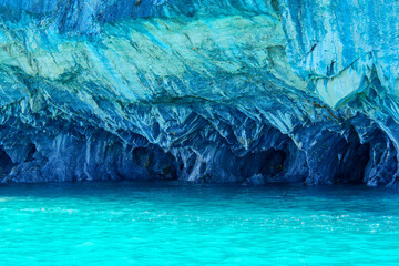 Turquoise water of General Cerrerra Lake splashing against blue Marble caves or Cuevas de Marmol at...