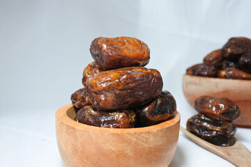 Dates fruit in a wooden bowl on a white background close up