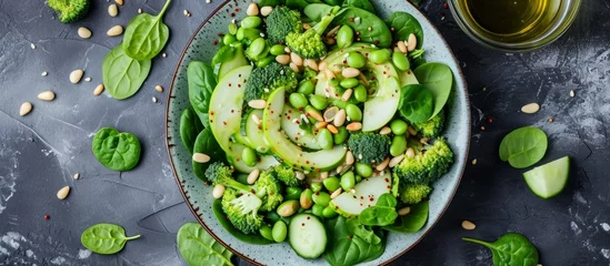 Deurstickers Green salad featuring spinach, broccoli, apples, cucumber, and edamame beans, served with avocado dressing, apple cider vinegar, olive oil, pine nuts, and pumpkin seeds. © 2rogan