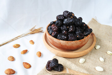 Ajwa dates fruit in wooden bowl on white background, selective focus