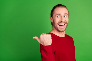 Portrait of funny guy with long hairstyle wear red sweatshirt look indicating at sale empty space isolated on green color background