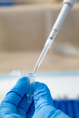 Dripping liquid from pipette into test tube in laboratory, closeup